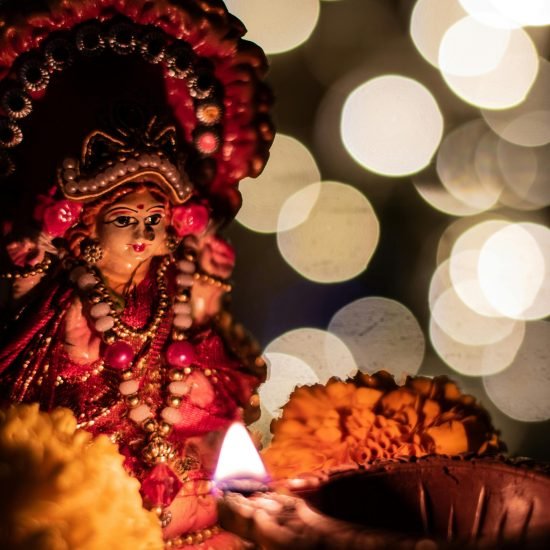 Close-up of a Hindu goddess statue lit by candlelight during a festival, highlighting cultural traditions.